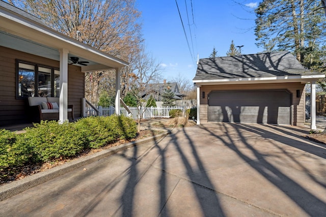 view of side of property with an outbuilding, a garage, a ceiling fan, and fence