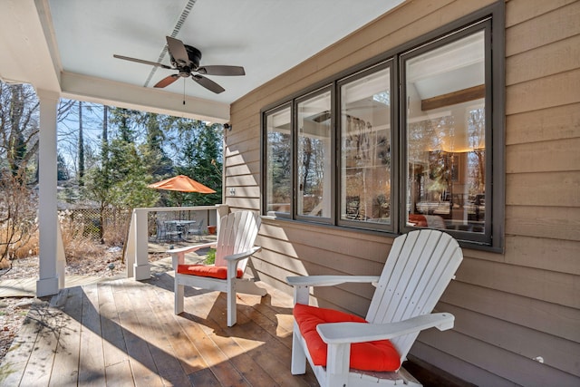 view of patio / terrace with a deck, ceiling fan, outdoor dining space, and fence