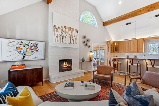 living room with a wealth of natural light, beamed ceiling, high vaulted ceiling, and light wood finished floors