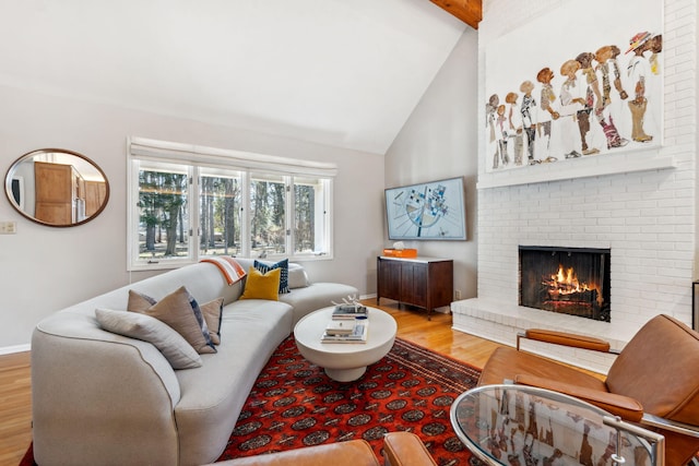 living room with beam ceiling, high vaulted ceiling, wood finished floors, baseboards, and a brick fireplace