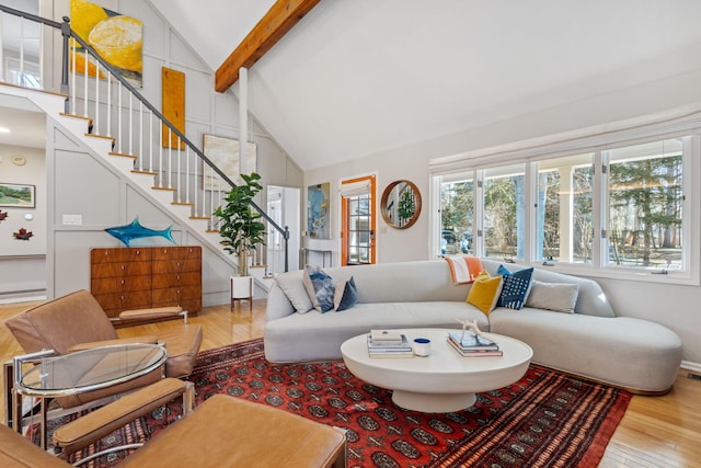 living area featuring beam ceiling, high vaulted ceiling, stairs, and wood finished floors