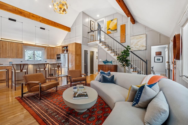 living area featuring stairway, beamed ceiling, high vaulted ceiling, and light wood-type flooring