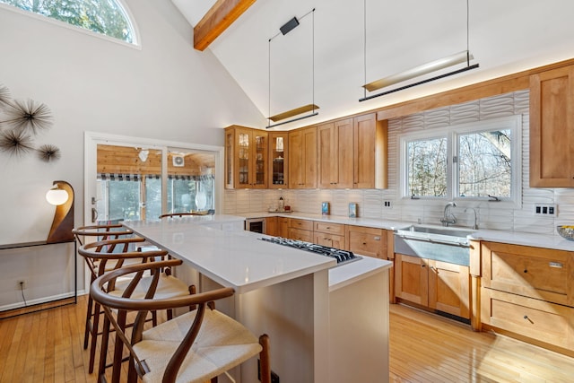 kitchen featuring a sink, decorative backsplash, a breakfast bar, and light wood finished floors