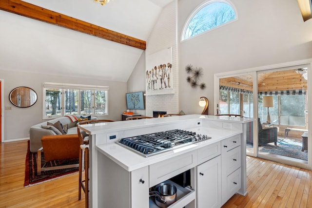 kitchen with stainless steel gas cooktop, open floor plan, light countertops, and light wood-type flooring