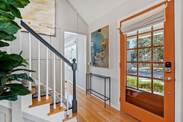 entrance foyer featuring stairs, vaulted ceiling, baseboards, and light wood-type flooring