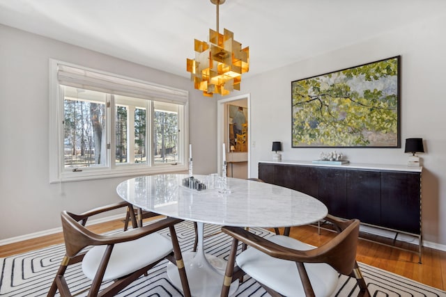 dining room featuring a chandelier, baseboards, and wood finished floors