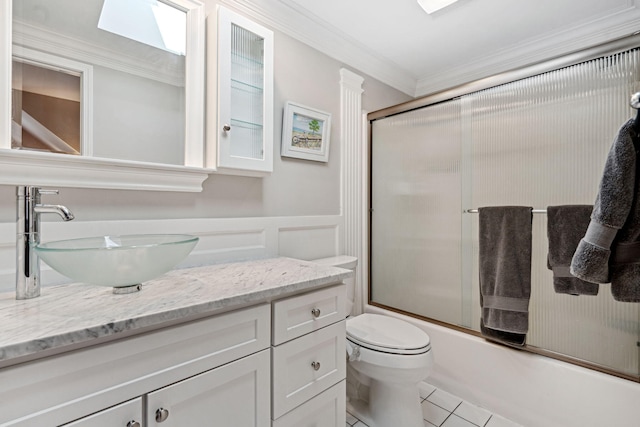 full bathroom with a wainscoted wall, ornamental molding, combined bath / shower with glass door, tile patterned flooring, and vanity