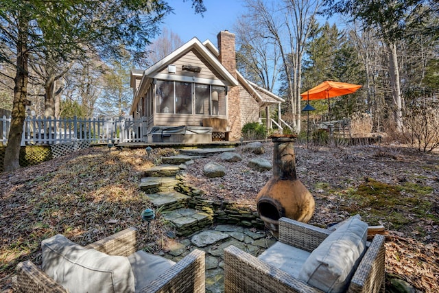 back of property featuring a chimney, a sunroom, and a wooden deck