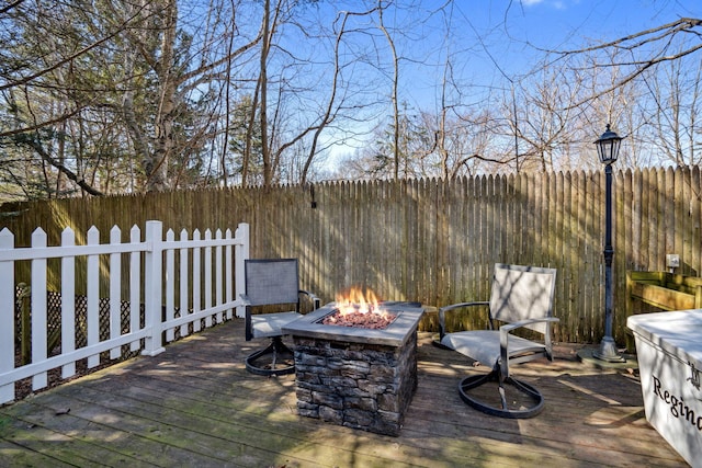 wooden deck with a fire pit and fence