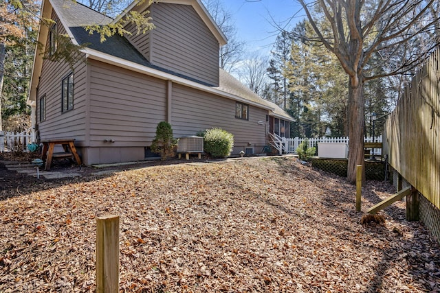 view of property exterior with central air condition unit, fence, a sunroom, and a shingled roof