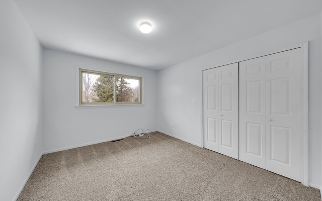 unfurnished bedroom with visible vents, baseboards, carpet, and a closet