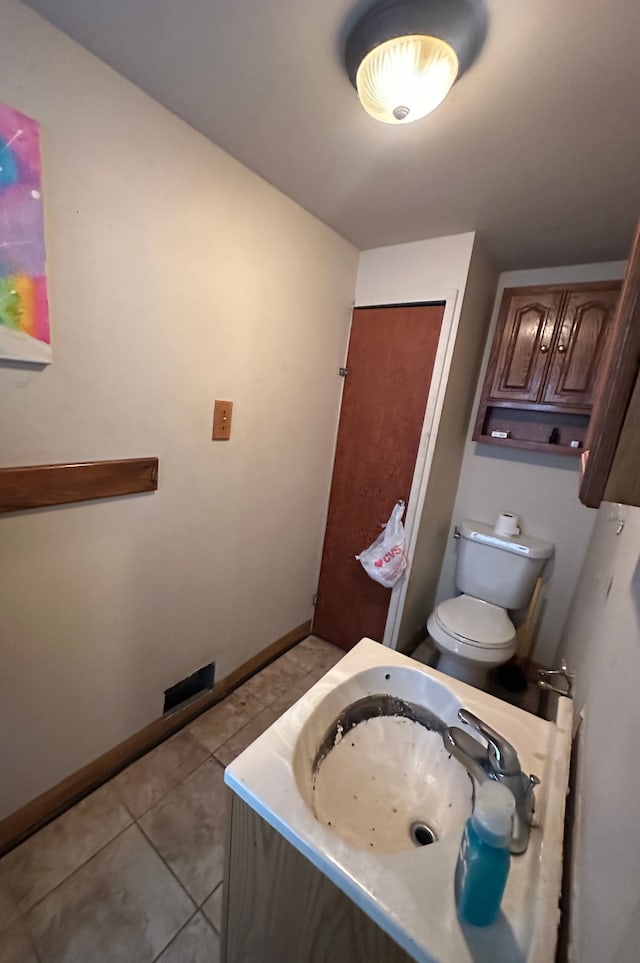 bathroom with tile patterned flooring, toilet, baseboards, and a sink