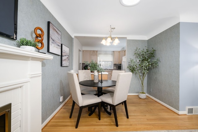 dining space featuring wallpapered walls, visible vents, a chandelier, and light wood finished floors