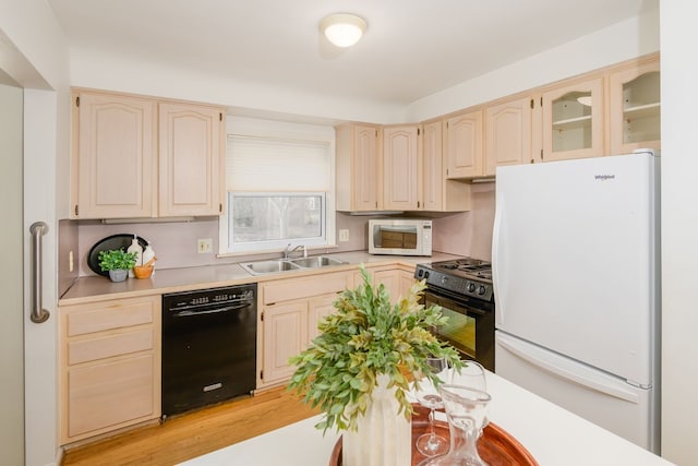 kitchen with black appliances, glass insert cabinets, light countertops, and a sink