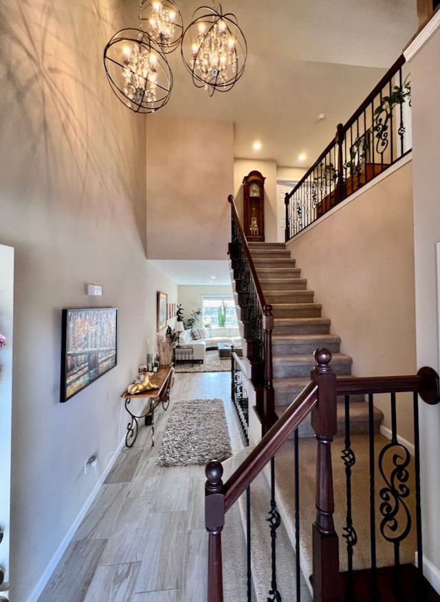 stairway with a chandelier, baseboards, and a towering ceiling