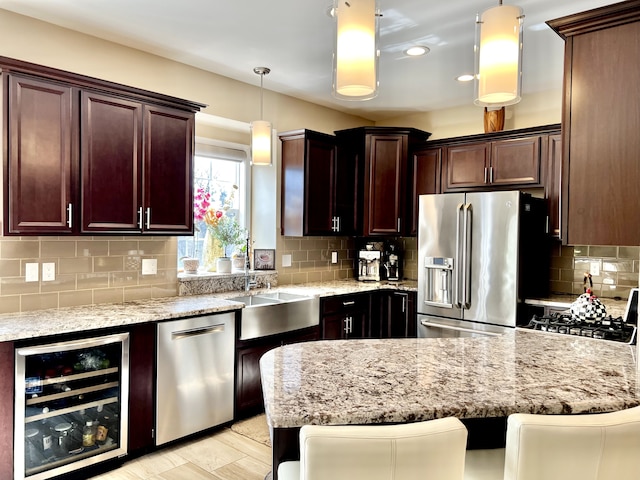 kitchen with beverage cooler, light stone countertops, stainless steel appliances, decorative light fixtures, and tasteful backsplash