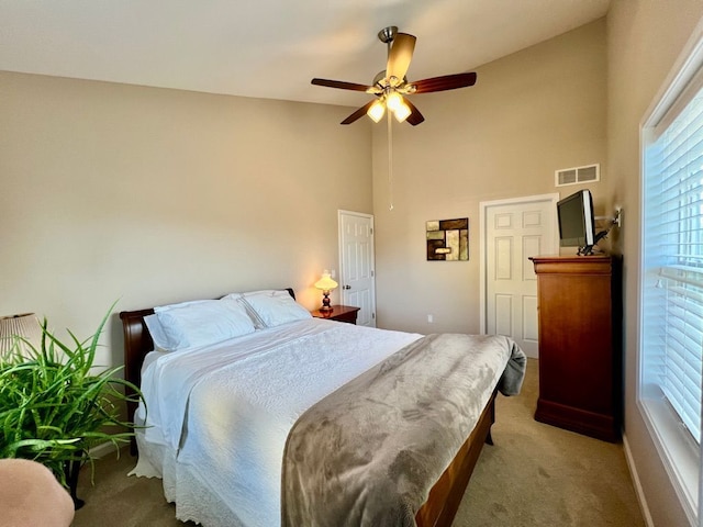 bedroom featuring a ceiling fan, baseboards, visible vents, high vaulted ceiling, and light colored carpet