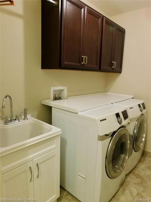 clothes washing area featuring washer and clothes dryer, cabinet space, and a sink