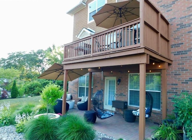 rear view of house with a patio area, a balcony, and brick siding