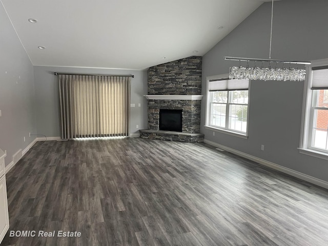 unfurnished living room with a stone fireplace, wood finished floors, and baseboards