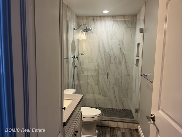 bathroom with a stall shower, toilet, vanity, and wood finished floors