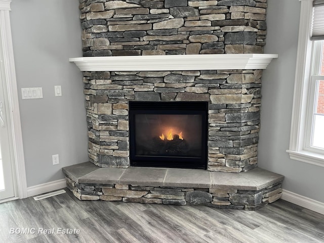 interior details featuring wood finished floors, a fireplace, visible vents, and baseboards