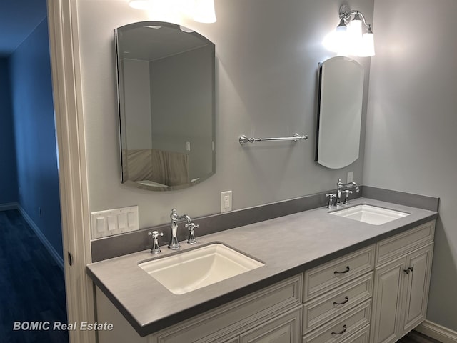 bathroom featuring a sink, baseboards, and double vanity