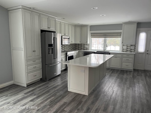 kitchen with a sink, gray cabinetry, light countertops, dark wood-type flooring, and appliances with stainless steel finishes