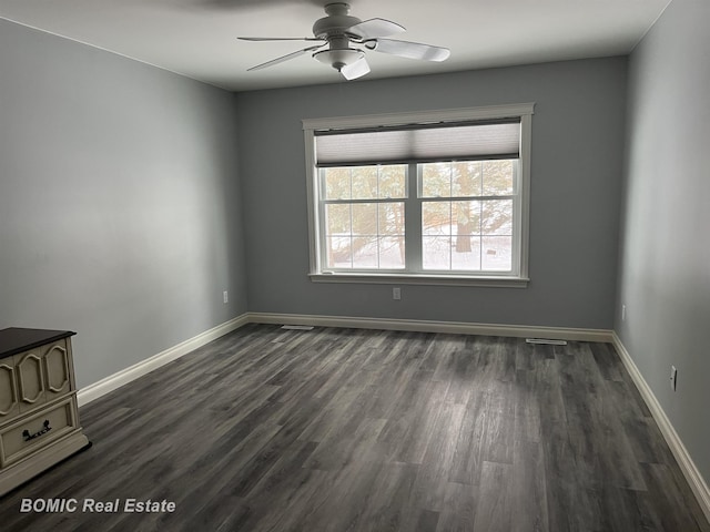 spare room featuring a ceiling fan, dark wood-type flooring, and baseboards