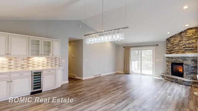 kitchen featuring open floor plan, visible vents, backsplash, light wood-style floors, and beverage cooler