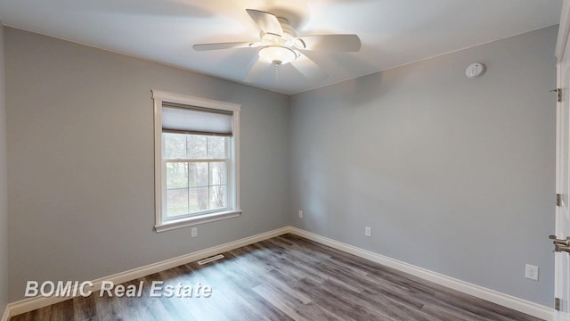 empty room featuring dark wood finished floors, visible vents, and baseboards