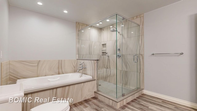 bathroom with a shower stall, toilet, and wood finished floors