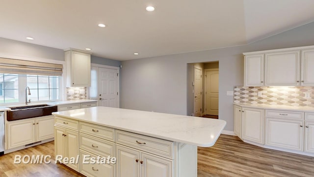 kitchen with recessed lighting, a sink, light wood-type flooring, a center island, and decorative backsplash