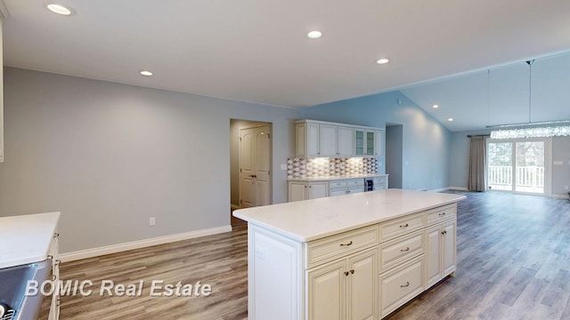 kitchen with light wood finished floors, baseboards, lofted ceiling, decorative backsplash, and light countertops