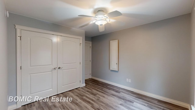 unfurnished bedroom with baseboards, a ceiling fan, wood finished floors, and a closet