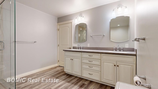 bathroom featuring wood finished floors, a sink, and a shower with shower door