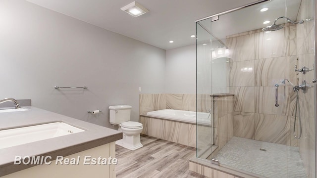 bathroom featuring wood finished floors, a marble finish shower, a sink, double vanity, and toilet