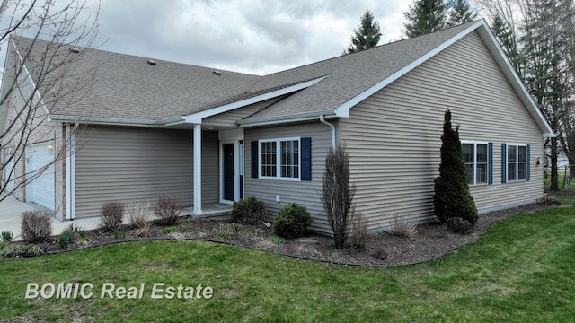 exterior space with a garage, a shingled roof, and a front lawn