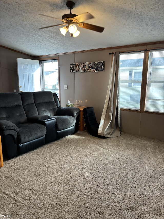 carpeted living area with a textured ceiling, a ceiling fan, and crown molding