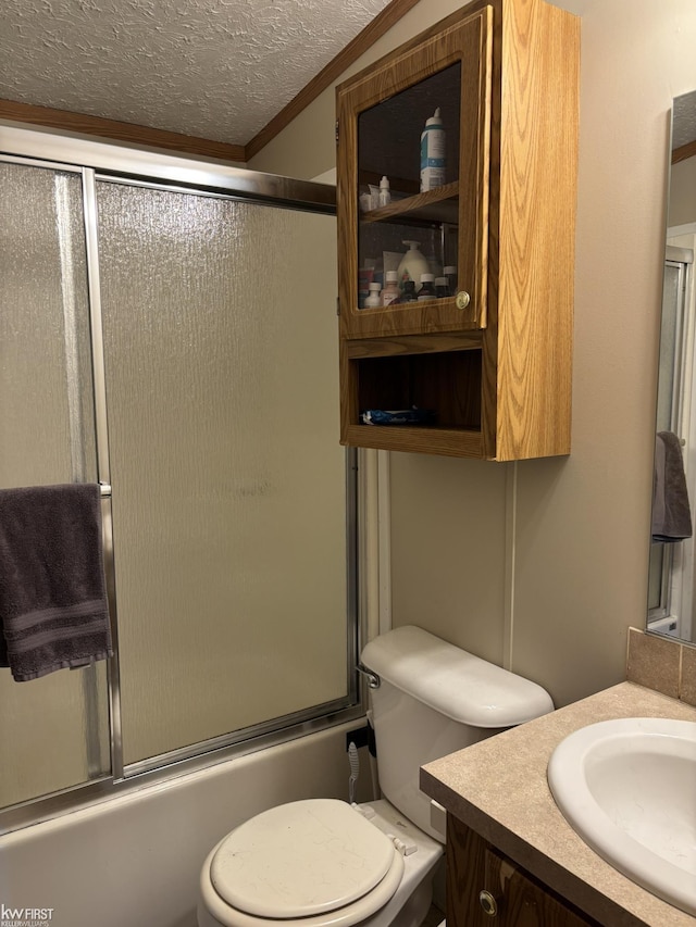 bathroom with combined bath / shower with glass door, vanity, a textured ceiling, and toilet