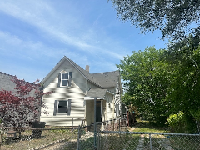 view of front of home featuring a fenced front yard, a chimney, and roof with shingles