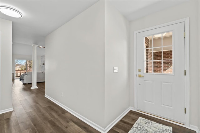 entryway featuring baseboards, dark wood-style floors, and ornate columns