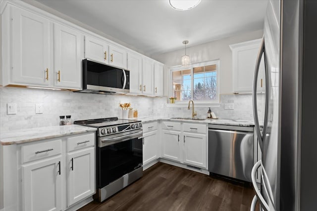 kitchen with a sink, light stone countertops, stainless steel appliances, white cabinetry, and dark wood-style flooring