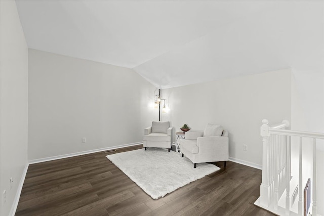 living area featuring vaulted ceiling, dark wood-style floors, and baseboards