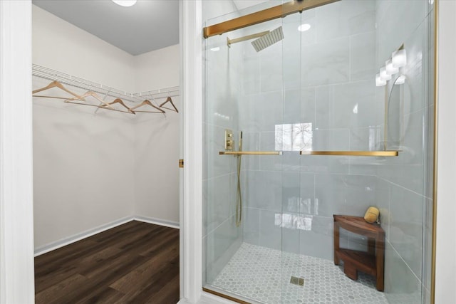 bathroom with a stall shower, baseboards, wood finished floors, and a spacious closet