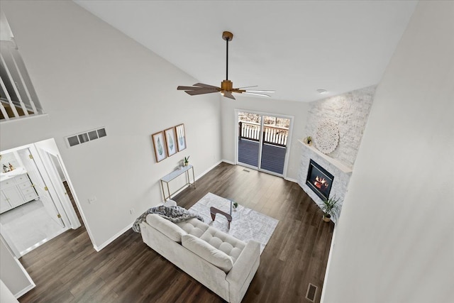 living room with wood finished floors, baseboards, visible vents, high vaulted ceiling, and a fireplace