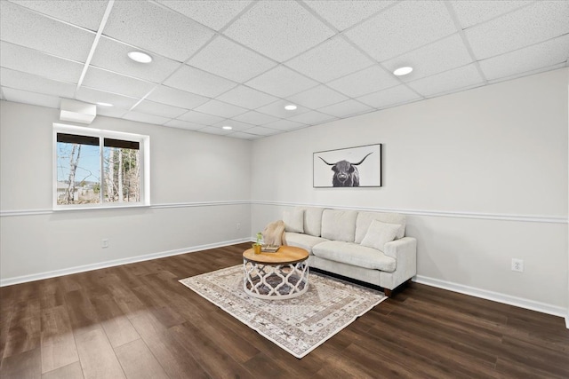 living area with a drop ceiling, baseboards, and wood finished floors