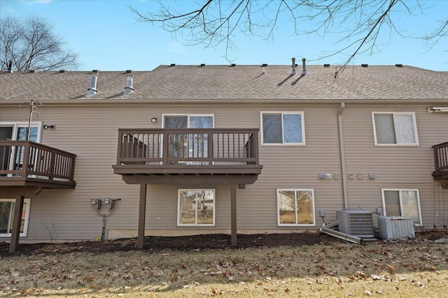 back of property with central AC unit and roof with shingles