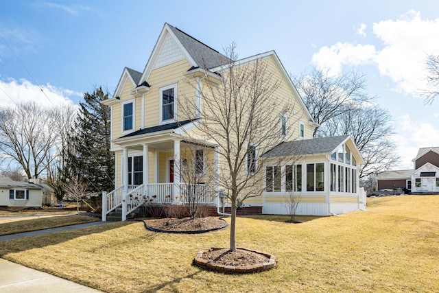 traditional-style house with a porch, a shingled roof, a front lawn, and a sunroom