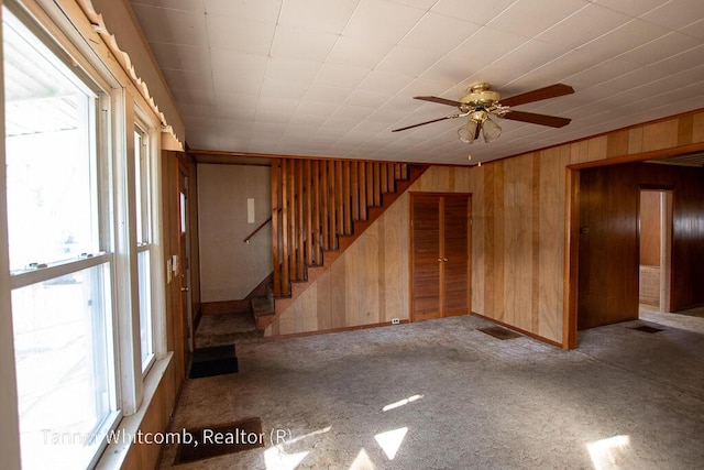 unfurnished living room featuring wooden walls, stairway, and carpet floors